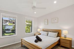 a bedroom with a large bed with two night stands and two windows at Scenic Shores in Budgewoi