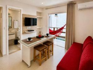 a living room with a red couch and a kitchen at Flats Morro de São Paulo in Morro de São Paulo