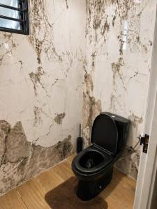 a bathroom with a black toilet and a marble wall at Southgate Residence in Paramaribo