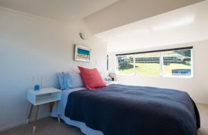 a bedroom with a bed and a window at Waiheke Waters Edge in Omiha