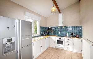a kitchen with white cabinets and a refrigerator at Authentique Maison Piscine in Saint-Amans-Valtoret