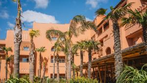 an orange building with palm trees in front of it at Hotel Tarifa Lances, a member of Radisson Individuals in Tarifa