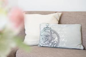 a pillow with a clock on it sitting on a couch at Haus Vogelflug strandleev3 in Fehmarnsund