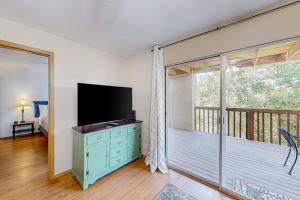 a living room with a television and a balcony at Treetop Tranquility in Branson