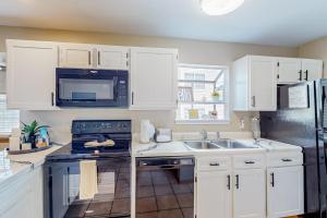a kitchen with white cabinets and a stove and a sink at Treetop Tranquility in Branson +30 photos