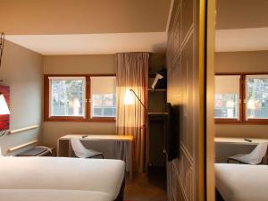 a room with two beds and a table and chairs at ibis Paris Bercy Village in Paris