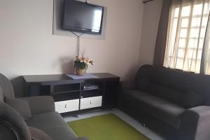 a living room with a couch and a tv at Casa do Bruno, 600 mt do thermas in Olímpia