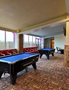 a room with two pool tables and red chairs at JJ chalet in Scratby