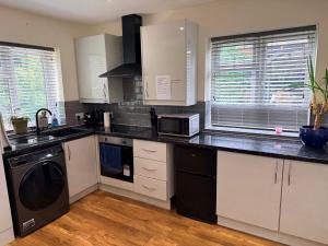 a kitchen with white cabinets and a black counter top at Chiltern Nursuries in Amersham
