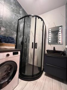 a bathroom with a shower and a washing machine at Apartament Raj in Biała Podlaska