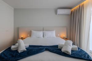 a bedroom with a large white bed with towels on it at Azor Signature Flats - IV in Ponta Delgada