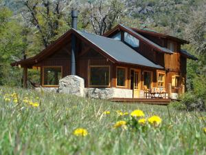 una cabaña de madera en el bosque con un campo de flores en Casa Lago Meliquina en Villa Meliquina