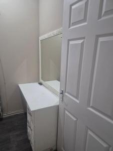 a white bathroom with a mirror and a door at BluSash in Durban