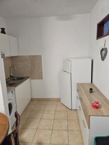 a kitchen with a white refrigerator and a table at Apartmani Kasteljan 2, Stara Novalja in Stara Novalja +3 photos
