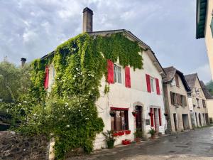 an ivy covered building with red shutters on a street at Maison Luard in Bedous