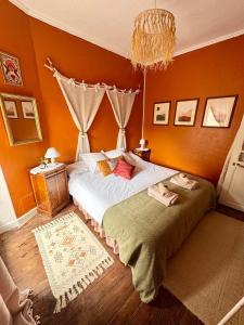 a bedroom with a large bed with orange walls at Maison Luard in Bedous