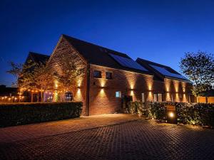 a brick building with lights on it at night at HVN10 - Near Antwerp in Stabroek