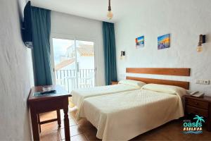 a hotel room with two beds and a window at Hotel Oasis Atalaya in Conil de la Frontera