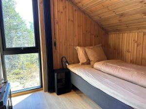 a bed in a wooden room with a window at Stryn Nature Lodge in Stryn