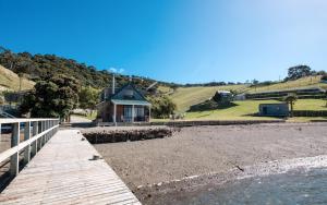 a wooden walkway leading to a building on a beach at Waiheke Waters Edge in Omiha