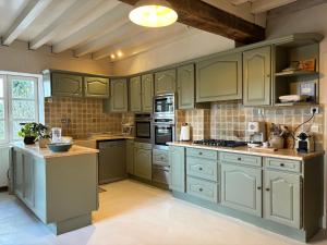 a large kitchen with green cabinets and appliances at Gite Authentique Évasion in Saint-Mard-de-Vaux