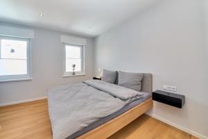 a bedroom with a bed and two windows at Burgblick Apartment Schieferblau in Bernkastel-Kues