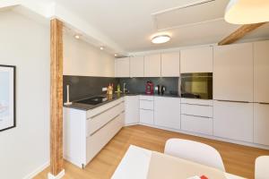 a white kitchen with white cabinets and a table at Burgblick Appartement Riesling Gold in Bernkastel-Kues