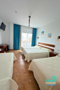 a hotel room with four beds with blue curtains at Hotel Oasis Atalaya in Conil de la Frontera