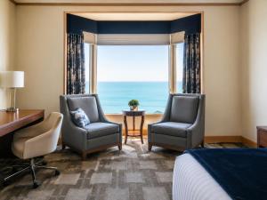 a hotel room with two chairs and a bed and a window at The Buckingham Hotel in Chicago