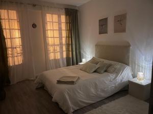 a bedroom with a white bed with two windows at Sand Home in Le Puy-en-Velay