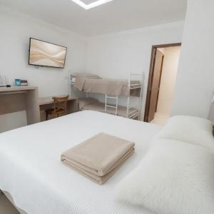 a white bed in a room with a desk at Bela Vista Hospedagem in Joinville