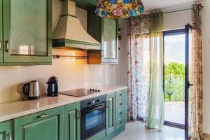 a kitchen with green cabinets and a window at Paradise Garden Villa in Bečići