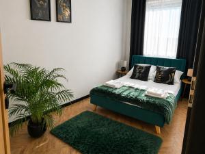 a bedroom with a green bed and a plant at Ami Luxury Residence XII CENTRUM - parking in Iława