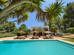 a pool with chairs and umbrellas in front of a house at Finca LA SELVA, Exclusive Villa in Benimussa in San Antonio