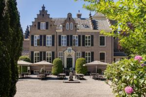 a large brick building with tables and umbrellas at Hotel Landgoed Zonheuvel in Doorn