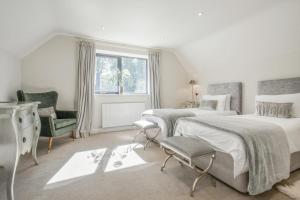 a white bedroom with two beds and a chair at 5 Bed in Hereford oc-78646 in Madley