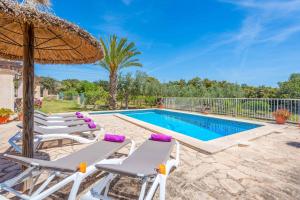 a villa with a swimming pool with two lounge chairs and an umbrella at Casa Catalina in Felanitx