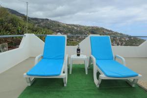 two blue chairs and a table on a balcony at Fifty`s House 1 By Sam Houses in Ribeira Brava