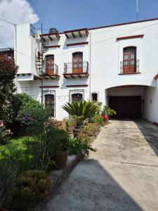 ein weißes Gebäude mit einer Garage und einigen Pflanzen in der Unterkunft Wulkan Studio in Amecameca de Juárez