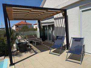 two blue chairs sitting under a pergola on a patio at Villa Marea in Nin
