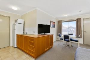 Comfort Inn Warrnambool International في وارنامبول: غرفة بها مكتب مع تلفزيون وطاولة مع كراسي