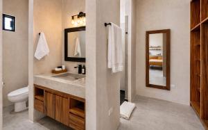 a bathroom with a sink and a toilet and a mirror at Ocean view terrace and saltwater pool group getaway in Todos Santos