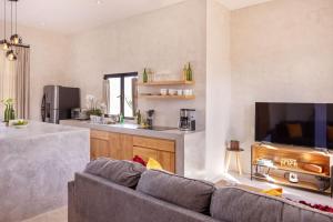 a living room with a gray couch and a kitchen at Sun-drenched escape w sleek saltwater pool in Todos Santos