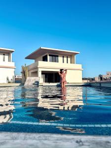 a person standing in the water in front of a house at Sun-drenched escape w sleek saltwater pool in Todos Santos +12 photos