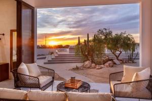a patio with a couch and chairs and a sunset at Sun-drenched escape w sleek saltwater pool in Todos Santos