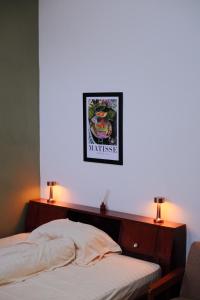a bedroom with a white wall with a bed and two lights at Atlasio House in Kasri