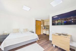 a white bedroom with a bed and a tv at Cozy Studio with a Garden in Gamsen