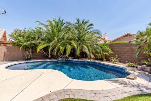 a swimming pool with palm trees in a backyard at Chandler Oasis in Chandler