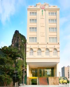a hotel building with a mountain in the background at Ha Long Park Hotel in Ha Long