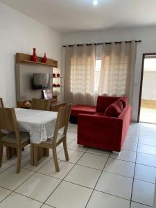 a living room with a table and a red couch at mazzonetto ap 03 in Primavera do Leste
